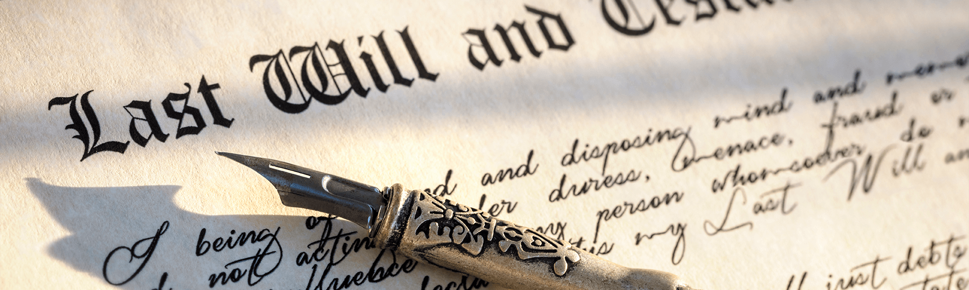 Antique ink pen lying on a paper with will and testament written in fancy lettering