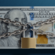 A stack of 100 dollar bills are covered by chains and a padlock