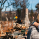 A man drapes his arm over a woman's shoulder as they face away from the camera. It appears they are looking at damage to a house and vehicle caused by a fire.